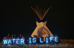 The Holders of the Light held several Idle No More water-related messages in front of the 2013 Indian Summer Festival's tipi, prominently located on the State Park Island in front of the Indian Summer grounds. (Photo: Light Brigading / Flickr)